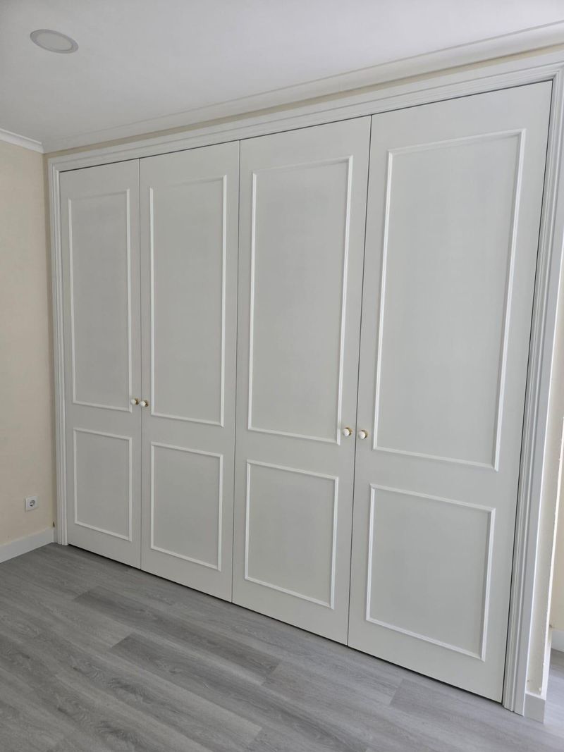 Roupeiro branco do chão ao teto com portas de batente molduradas.